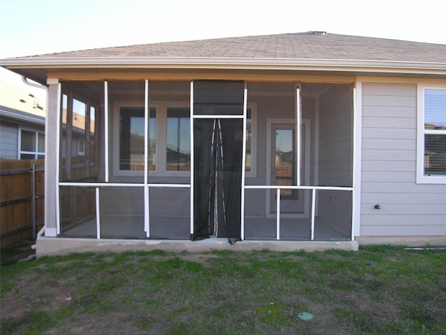 rear view of property featuring a lawn and a sunroom