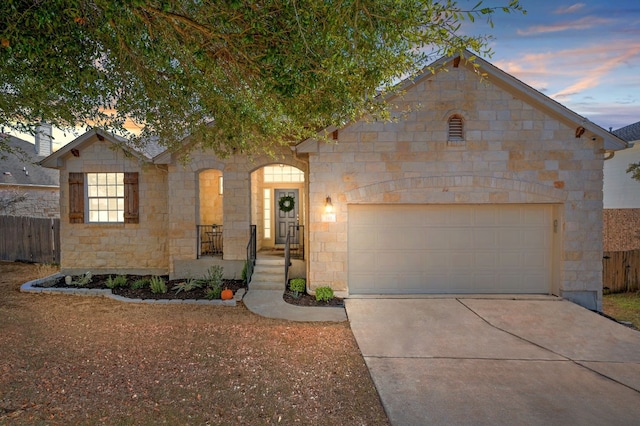 view of front of house featuring stone siding, concrete driveway, fence, and an attached garage