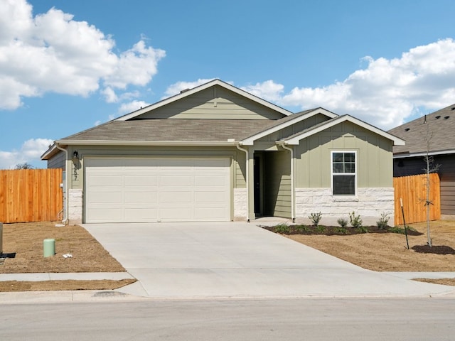 single story home with driveway, a garage, stone siding, fence, and board and batten siding