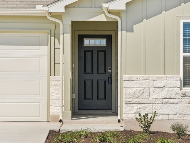 entrance to property with stone siding and an attached garage