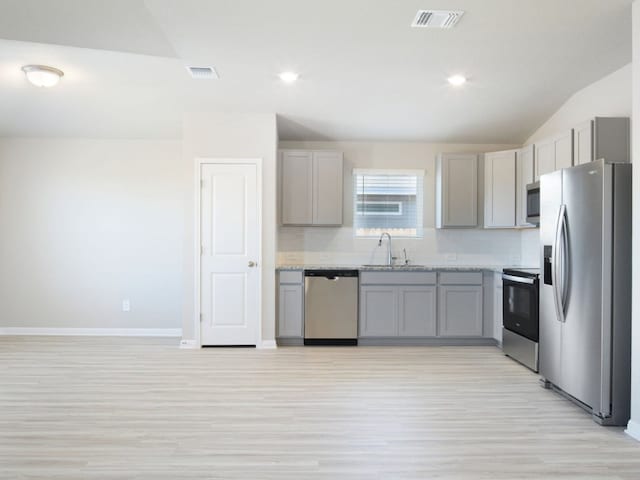 kitchen featuring stainless steel appliances, tasteful backsplash, visible vents, gray cabinetry, and a sink