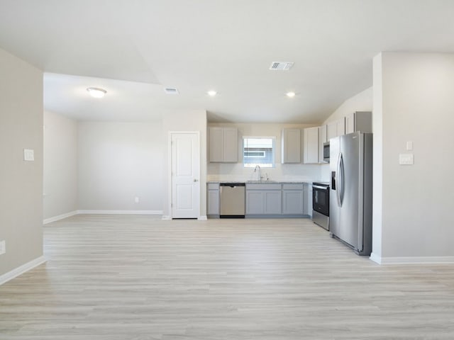 kitchen with stainless steel appliances, gray cabinets, visible vents, open floor plan, and a sink