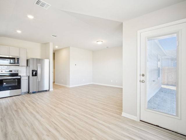 kitchen featuring stainless steel appliances, tasteful backsplash, light wood-type flooring, and visible vents