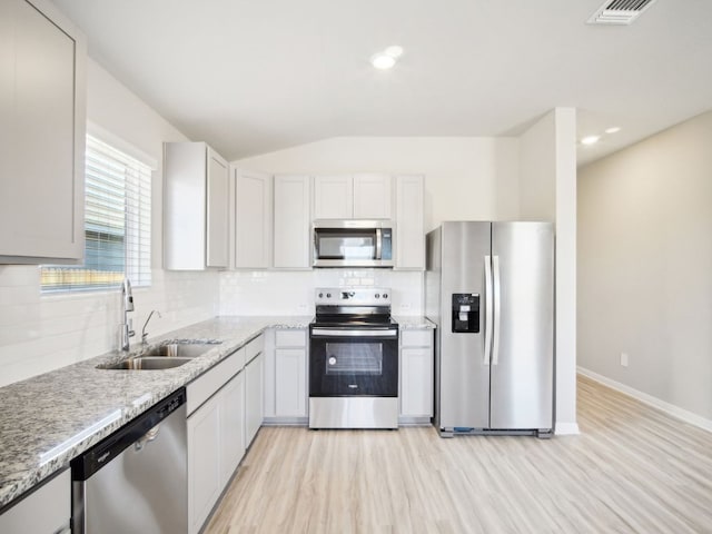 kitchen with visible vents, decorative backsplash, appliances with stainless steel finishes, vaulted ceiling, and a sink