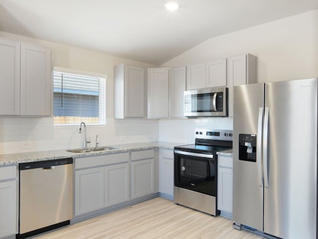 kitchen with decorative backsplash, appliances with stainless steel finishes, vaulted ceiling, and a sink