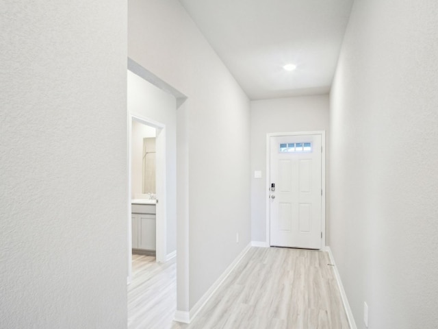 entryway featuring light wood-type flooring, a sink, and baseboards