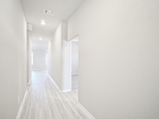 hallway with light wood-style flooring, recessed lighting, visible vents, and baseboards