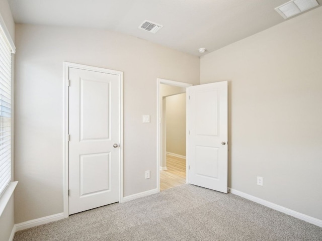 unfurnished bedroom featuring carpet floors, multiple windows, and visible vents