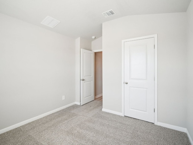 unfurnished bedroom with lofted ceiling, baseboards, visible vents, and light colored carpet