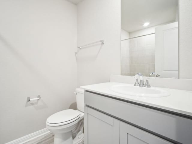 bathroom with baseboards, vanity, toilet, and wood finished floors