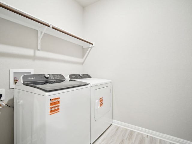 laundry room with laundry area, light wood-type flooring, washing machine and clothes dryer, and baseboards