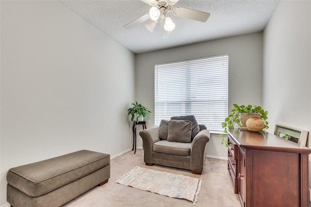 living area with light carpet, ceiling fan, and a textured ceiling