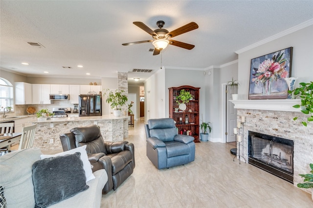 living room with ornamental molding, a fireplace, sink, and a textured ceiling