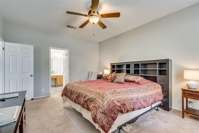 carpeted bedroom with ceiling fan, connected bathroom, and a textured ceiling