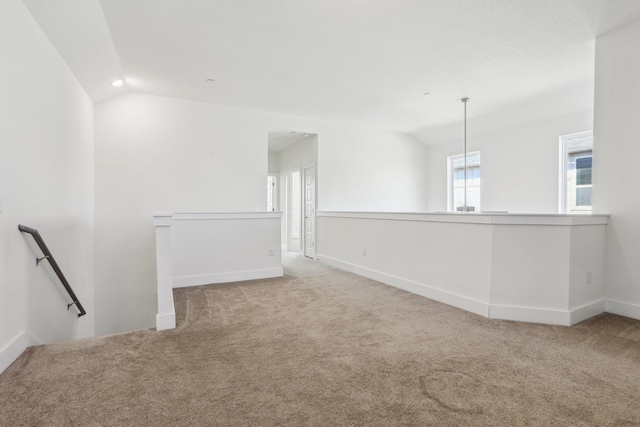 carpeted spare room with vaulted ceiling