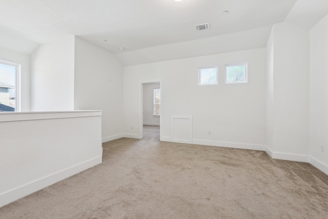 empty room featuring lofted ceiling and light carpet