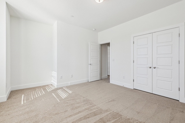 unfurnished bedroom featuring light colored carpet and a closet