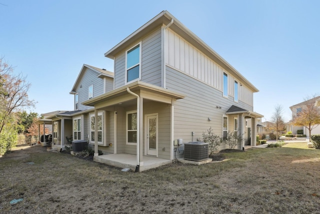 rear view of property with cooling unit, a patio area, and a lawn