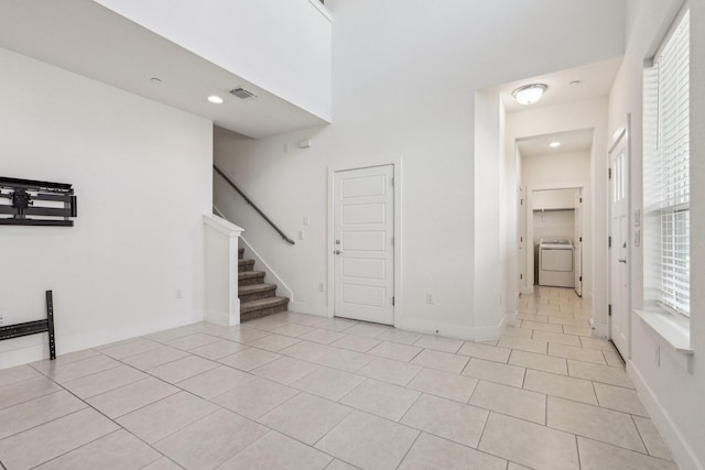 interior space with a towering ceiling, washer / dryer, and light tile patterned floors