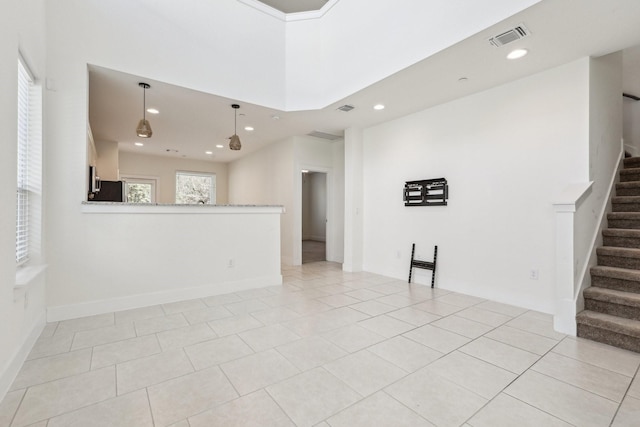 unfurnished living room with a wealth of natural light, a towering ceiling, and light tile patterned floors