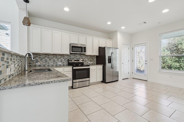 kitchen featuring light stone countertops, white cabinetry, appliances with stainless steel finishes, and sink