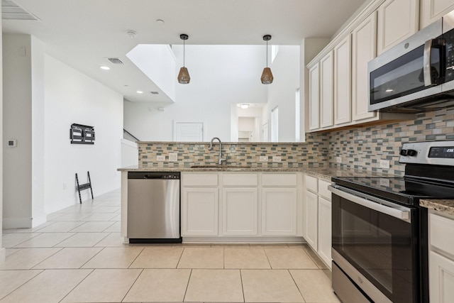 kitchen featuring appliances with stainless steel finishes, pendant lighting, white cabinetry, sink, and light stone counters