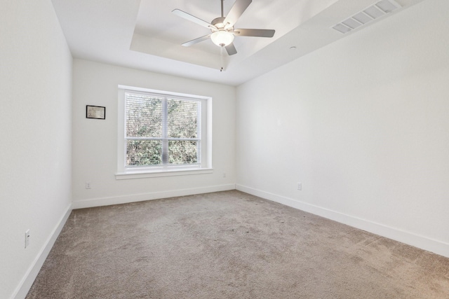 carpeted empty room with a raised ceiling and ceiling fan