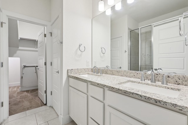 bathroom with tile patterned flooring, vanity, and walk in shower