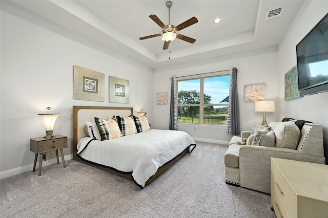 carpeted bedroom featuring ceiling fan and a raised ceiling