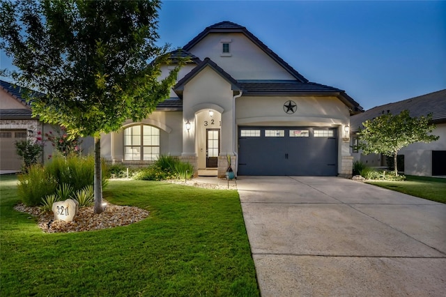 view of front facade featuring stucco siding, a front yard, a garage, stone siding, and driveway