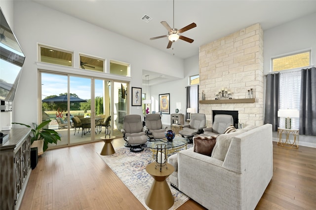 living room with wood-type flooring, a stone fireplace, and a wealth of natural light