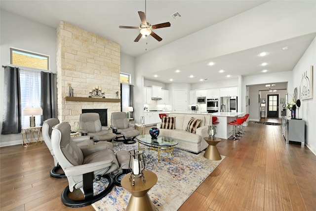 living room with wood-type flooring, a fireplace, visible vents, and baseboards