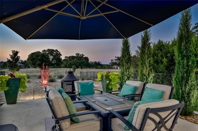 patio terrace at dusk featuring outdoor lounge area and fence