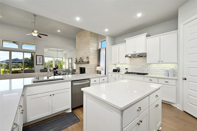 kitchen featuring appliances with stainless steel finishes, white cabinetry, sink, backsplash, and a center island