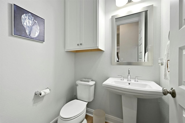 bathroom with toilet, baseboards, and a sink