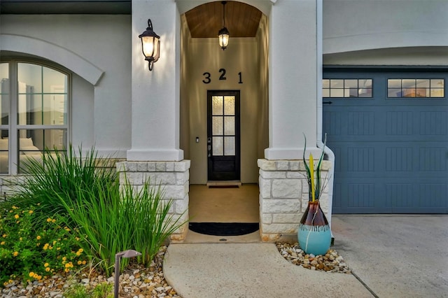 view of exterior entry featuring a garage and stucco siding