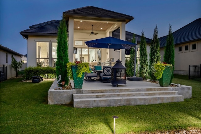 back of property with a tile roof, stucco siding, a lawn, a patio area, and ceiling fan