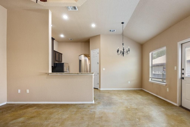 kitchen with stainless steel refrigerator, hanging light fixtures, dark brown cabinets, kitchen peninsula, and a chandelier