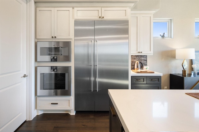 kitchen featuring stainless steel appliances, white cabinets, dark hardwood / wood-style flooring, and decorative backsplash