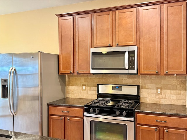 kitchen with tasteful backsplash, stainless steel appliances, and dark stone counters