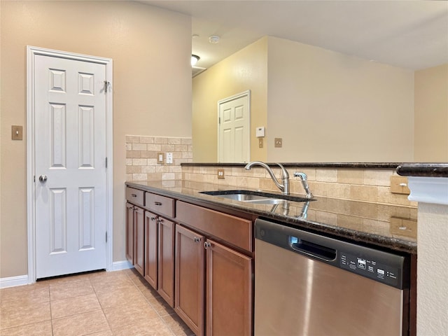 kitchen featuring light tile patterned flooring, tasteful backsplash, dishwasher, sink, and dark stone countertops