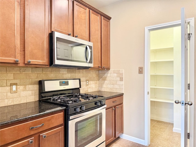 kitchen featuring decorative backsplash, stainless steel appliances, and dark stone counters