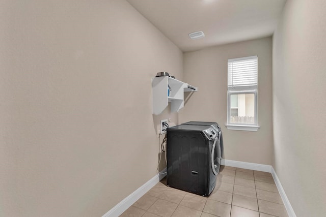 clothes washing area with light tile patterned floors and independent washer and dryer