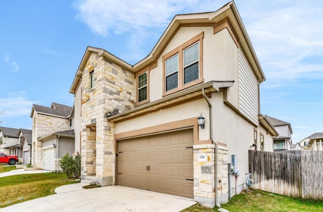 view of front facade with an attached garage, fence, stone siding, driveway, and stucco siding