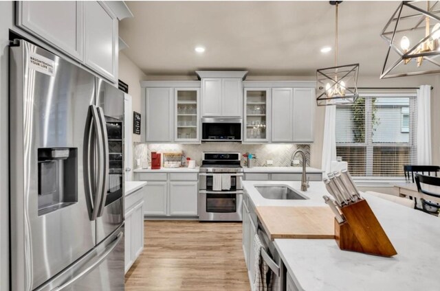 kitchen featuring sink, white cabinetry, appliances with stainless steel finishes, pendant lighting, and decorative backsplash