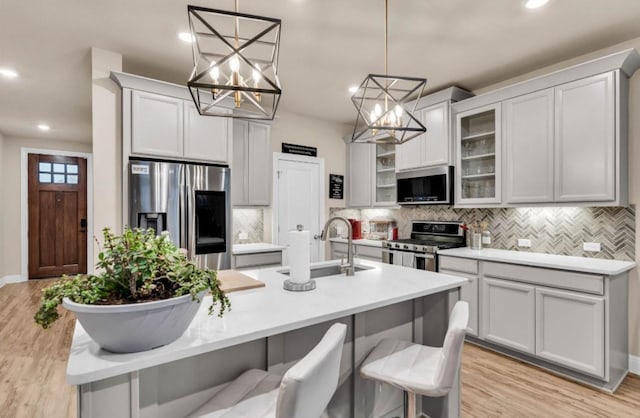 kitchen with hanging light fixtures, appliances with stainless steel finishes, sink, and a breakfast bar