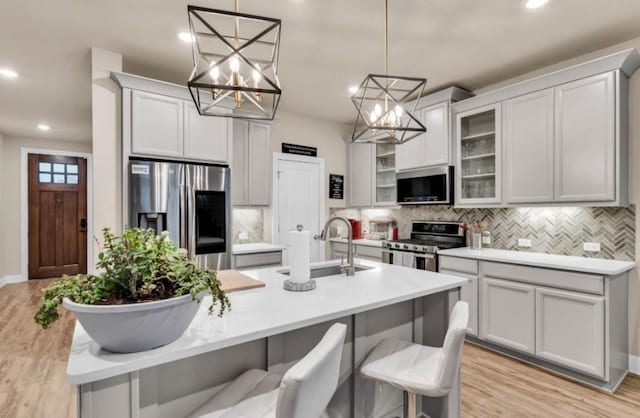 kitchen with light wood-style floors, appliances with stainless steel finishes, backsplash, and a sink