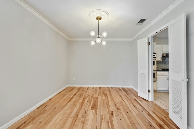 unfurnished dining area featuring ornamental molding, light wood-type flooring, and a chandelier