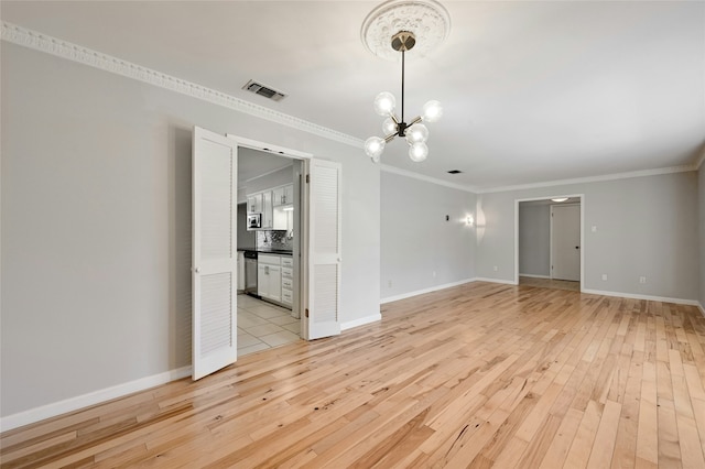 empty room featuring ornamental molding, a chandelier, and light hardwood / wood-style floors