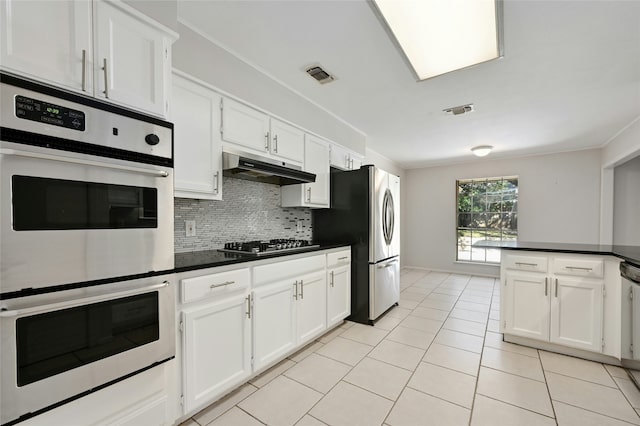 kitchen with light tile patterned floors, decorative backsplash, white cabinets, and appliances with stainless steel finishes